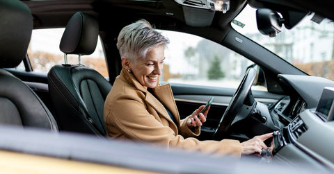 Active bestager women is using smart phone to start a sharing car
