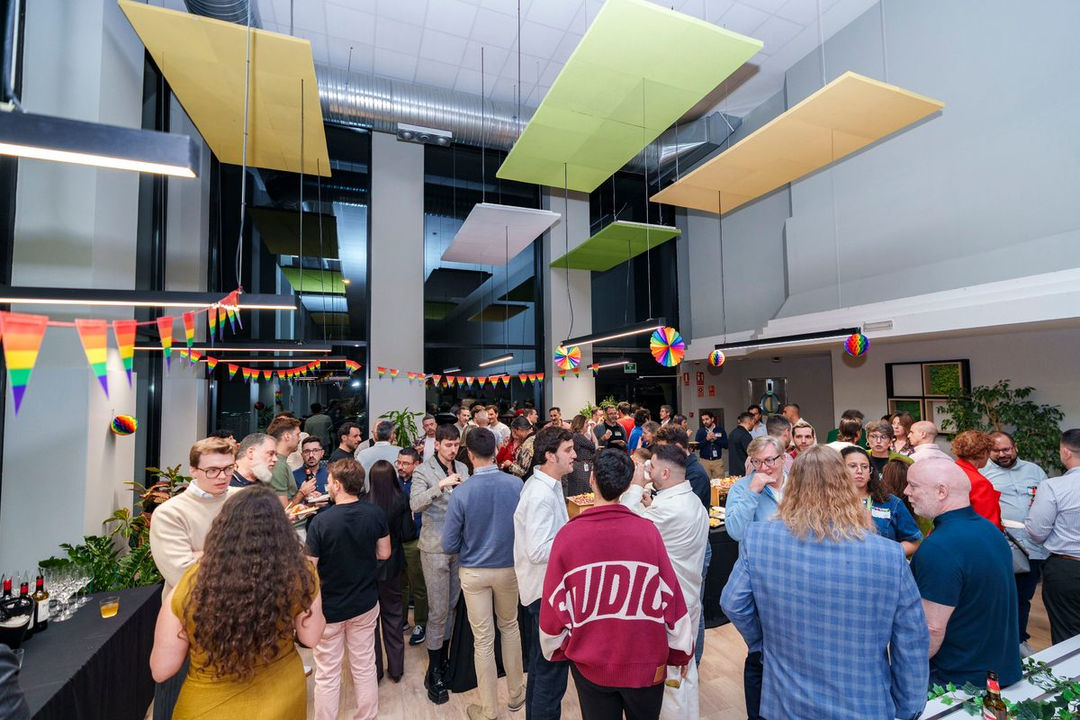 RTCE attendees networking in a large indoor space decorated with rainbow bunting and colorful hanging decorations.