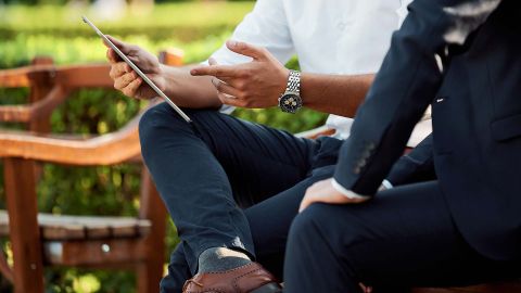 Couple standing around a blue pool at a hotel surrounded by sand. 