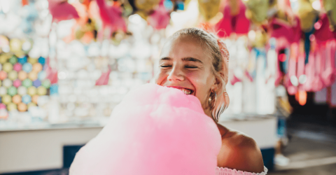a young, happy girl eating pink candyfloss