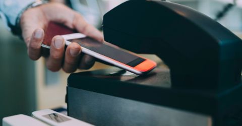 Male traveler tapping phone at airport check-in