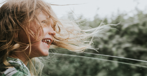 young girl smiling, looking out of window
