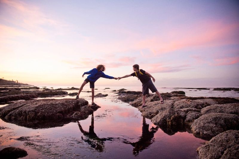 boys-help-each-other-across-tidal-pools-at-sunset