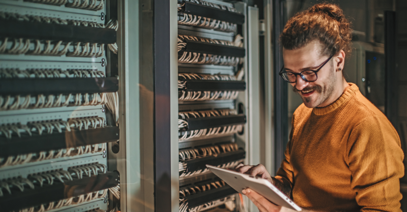 IT professional examining a tablet computer and server