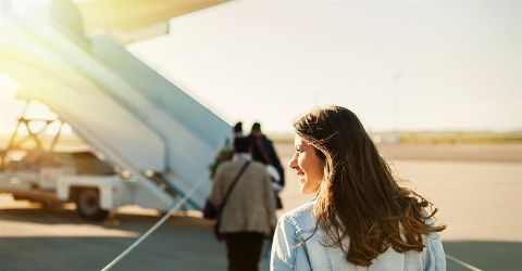 Image to support the blog. A girl and passengers on the runway walking towards an  airplane. 