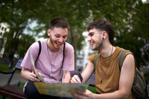 A gay couple laugh and look at a map as they enjoy their trip