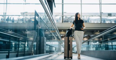 Asian woman with suitcase going through airport