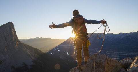 Mountaineer spreads arms to celebrate at mountain summit