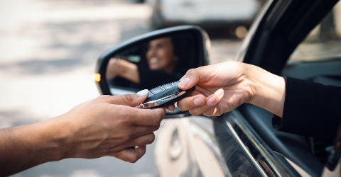 Car rental agency employee giving car keys to beautiful young woman