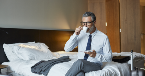 Business man in suit drinking coffee in hotel room