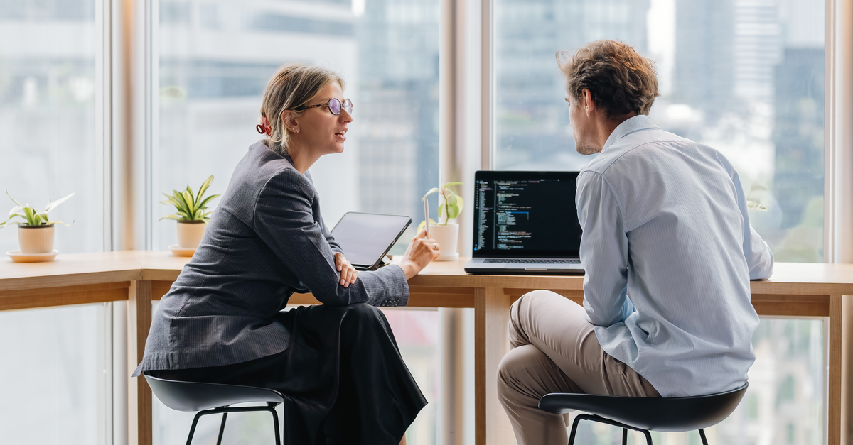 Two people looking at code on a laptop