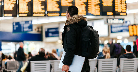 Man in airport looking at airline flight schedules