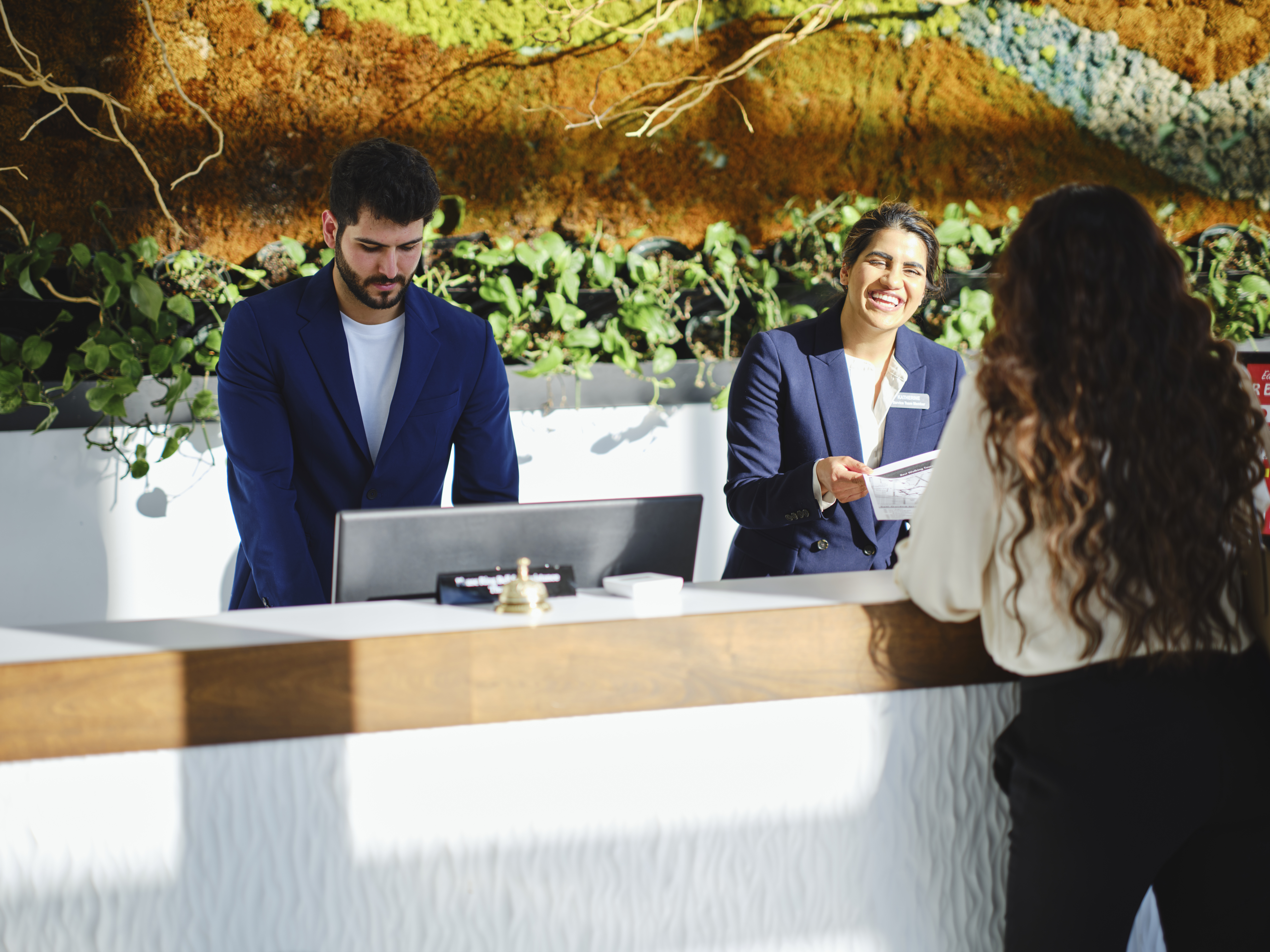 Hotel reception staff smiling and greeting a guest